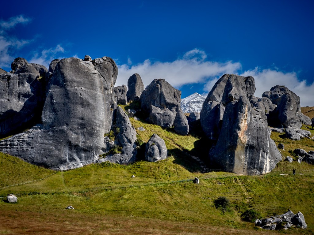 New Zealand 63 Massive gray limestone formations rise from grassy hills beneath a bright blue Canterbury sky.