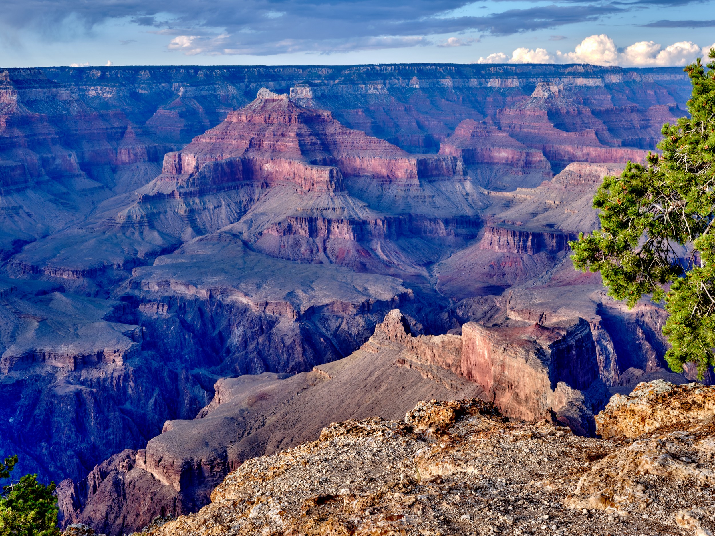 A view east from Hopi Point shows colorful Grand Canyon layers glowing beneath a blue sky.