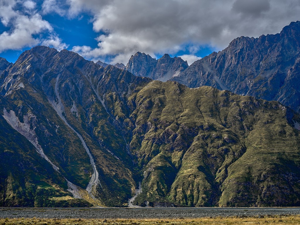 New Zealand 59 Rugged brown and gray mountain slopes climb sharply from the lake basin.