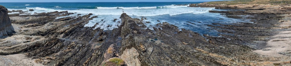 Panoramic coastal view with dramatic eroded rock formations and blue ocean