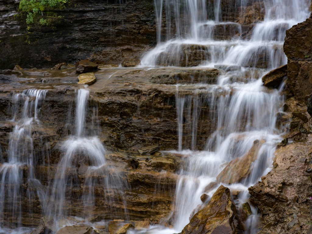 Close view of cascading water spreading over layered stone ledges with soft motion blur.