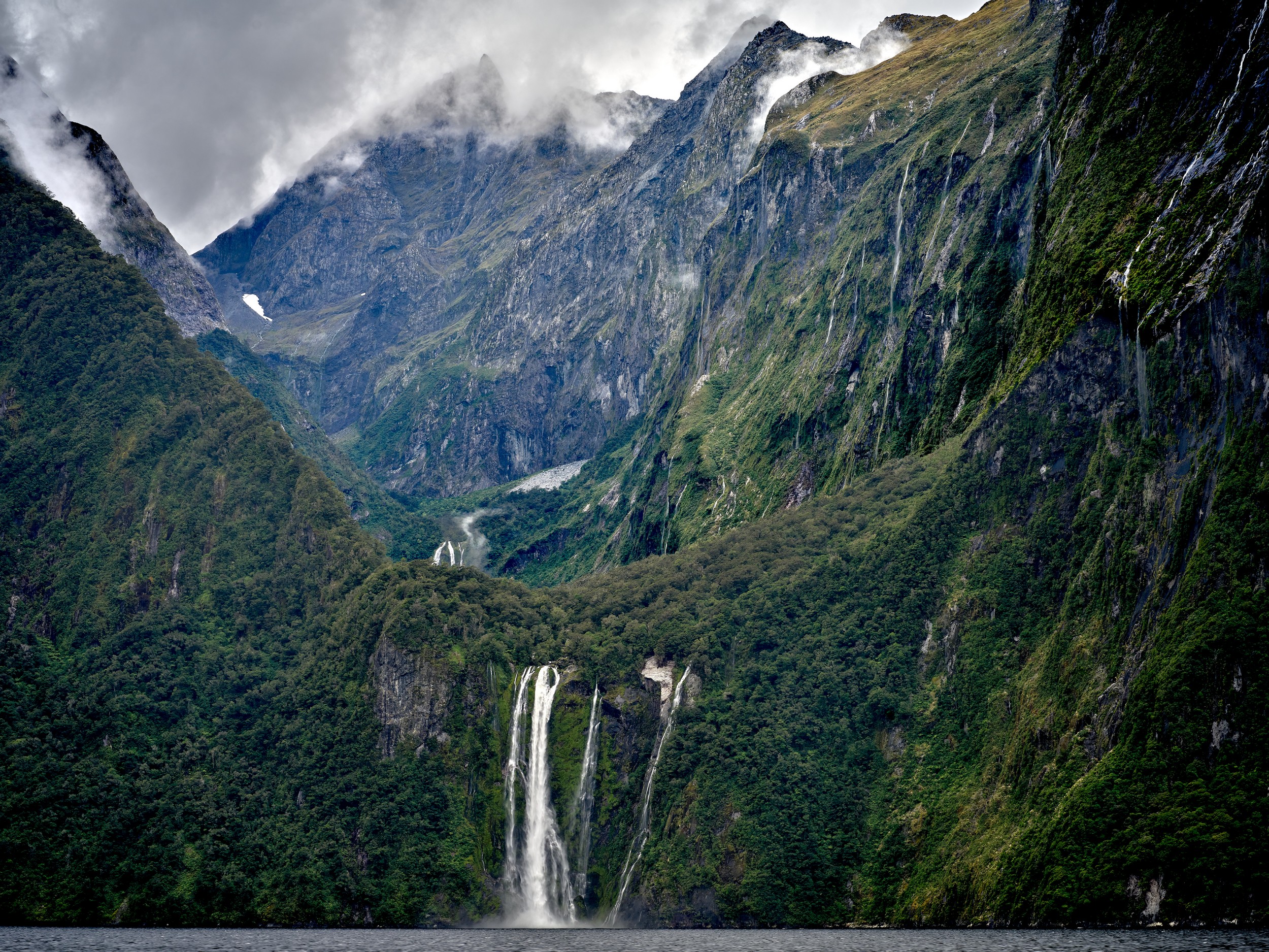 Milford Sound 9 A high waterfall drops from a glacier-carved hanging valley into the deep green walls of Milford Sound.