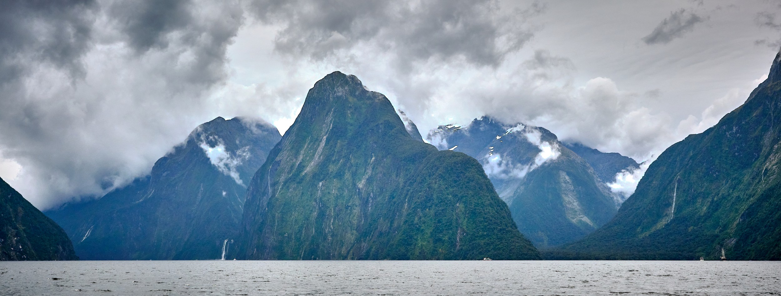 Milford Sound 23 A wide view shows steep mountain peaks and waterfalls rising from the waters of Milford Sound.