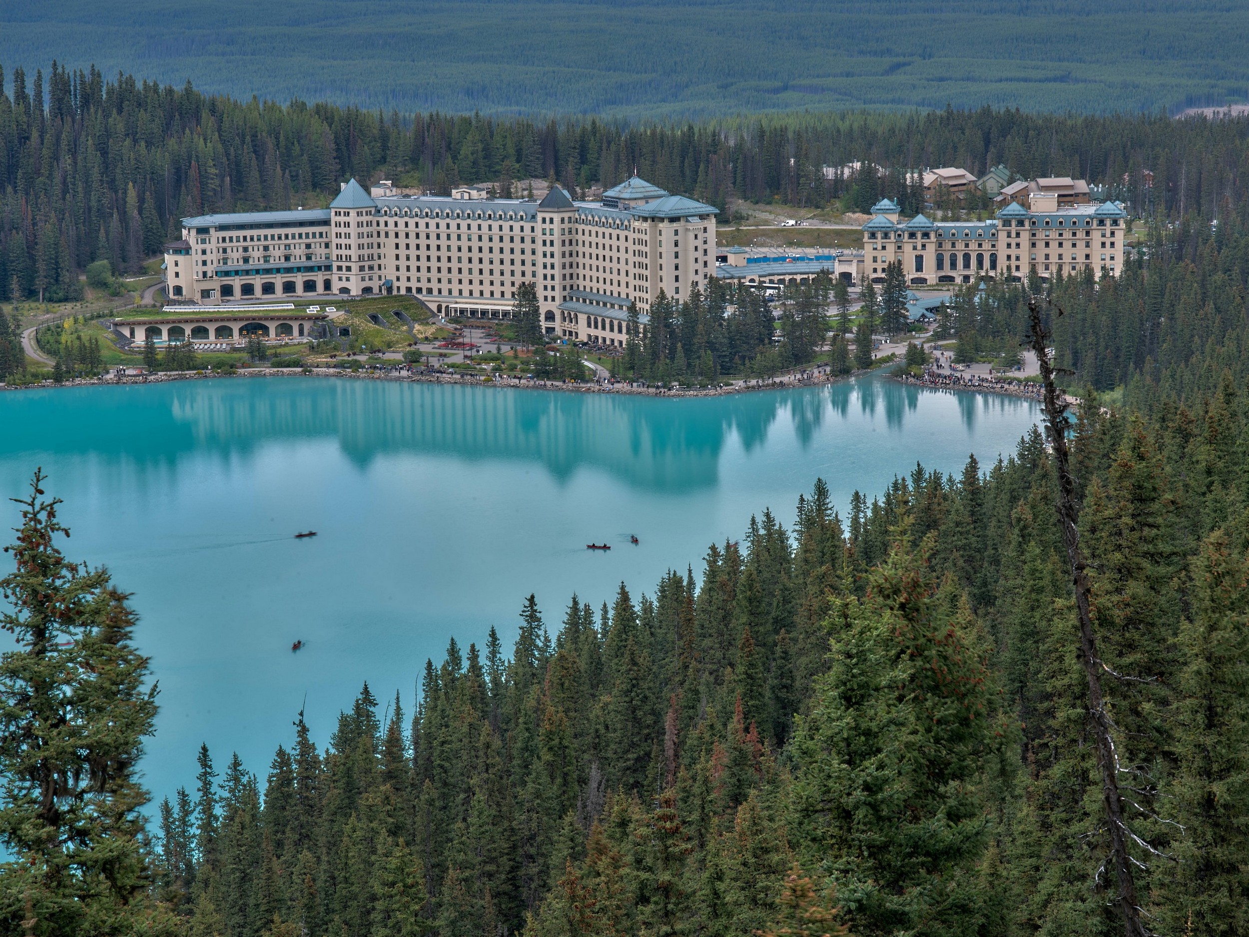 Turquoise Lakes 5 The large lakeside hotel sits beside bright turquoise Lake Louise, enclosed by dense evergreen forest.