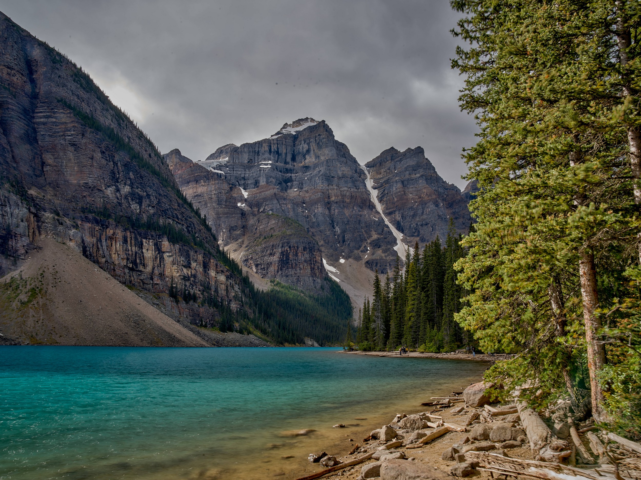 Turquoise Lakes 12 Clear turquoise water, sunlit shoreline trees, and the craggy Ten Peaks define a bright Moraine Lake scene.