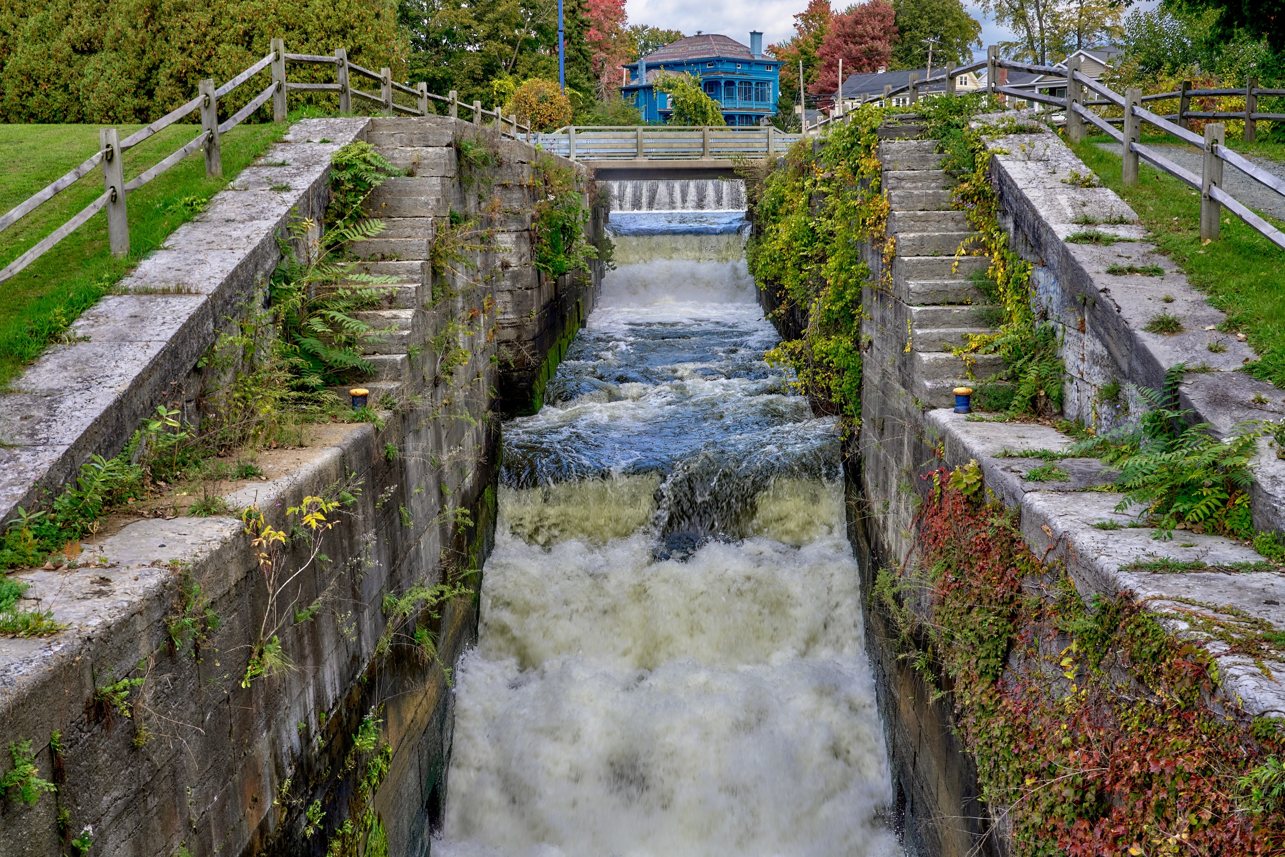 Vermont and Quebec 30 White water surges through a narrow masonry lock channel bordered by stone walls and railings.