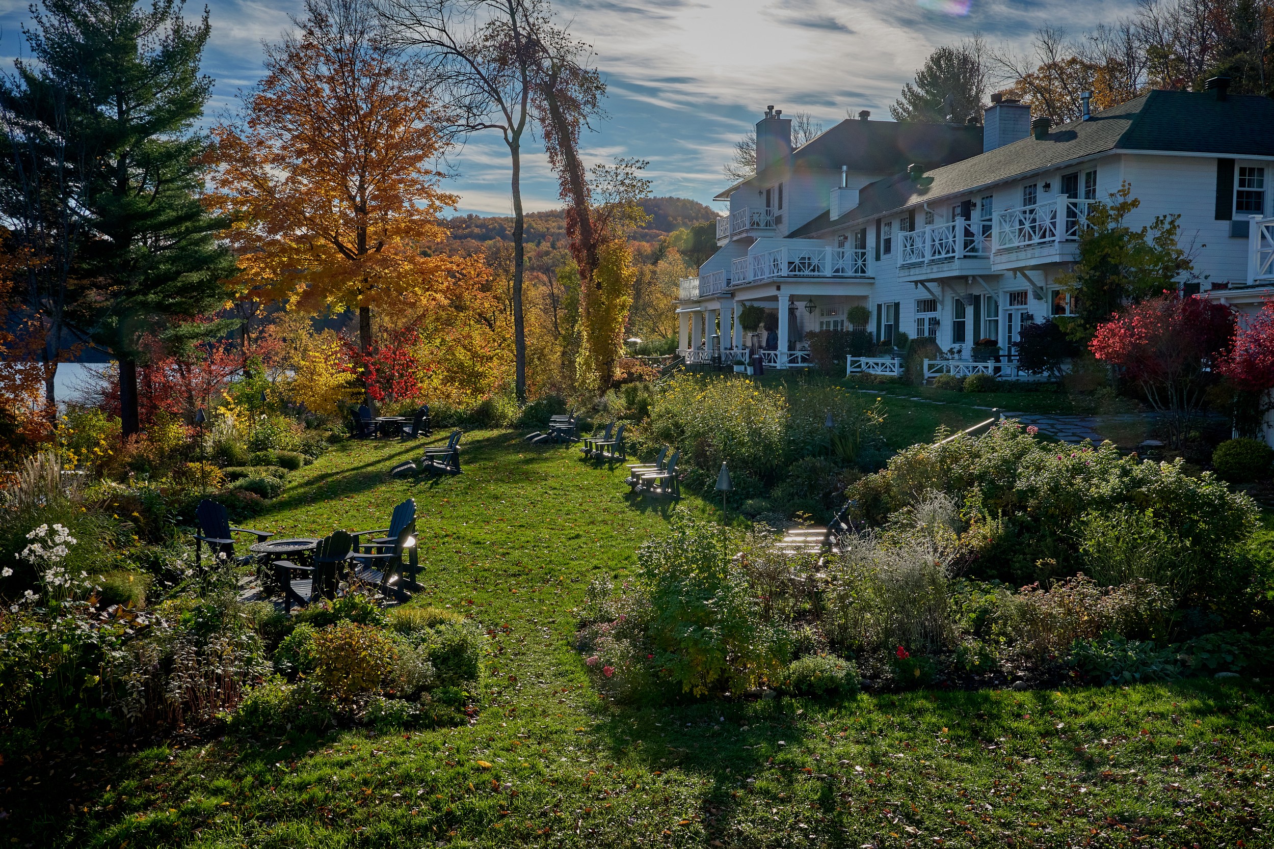Vermont and Quebec 69 The white Manoir Hovey building rises beyond garden beds, benches and autumn trees on the lakeside grounds.