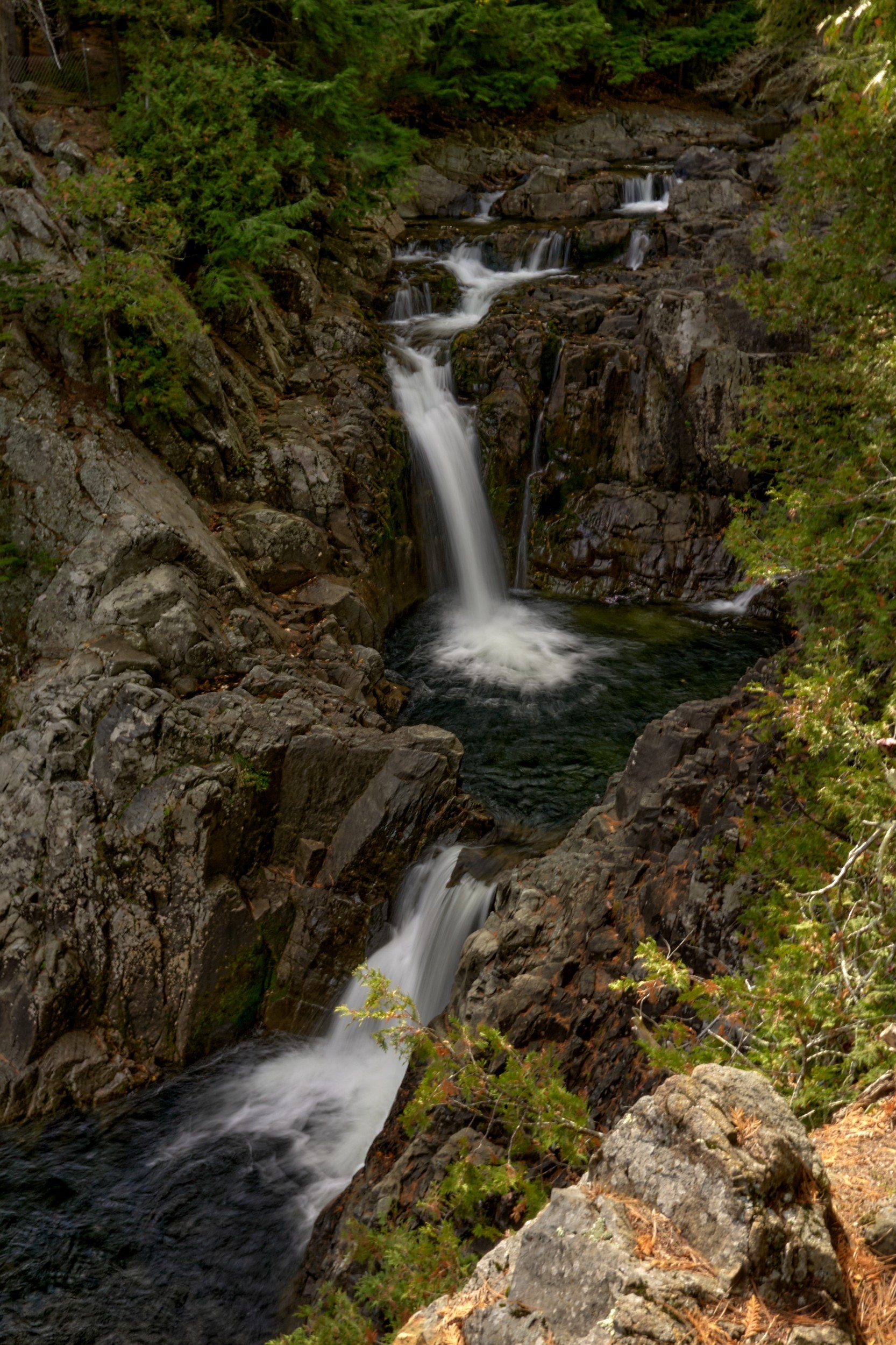 Vermont and Quebec 47 A narrow waterfall descends over dark rock into a small gorge surrounded by evergreen forest.